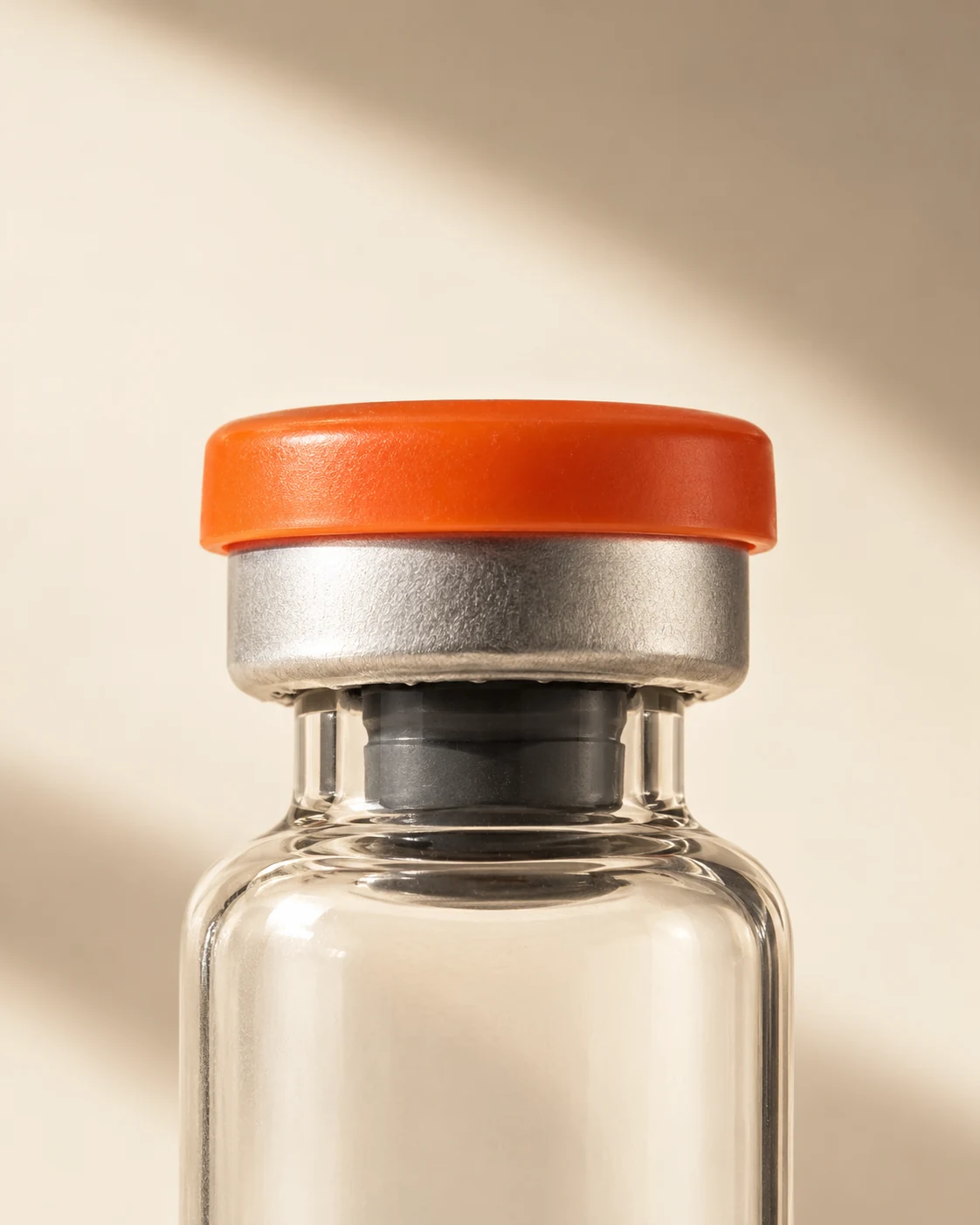 Studio-edited close-up of the orange cap, silver crimped seal and clear glass neck, based on our vial photograph.